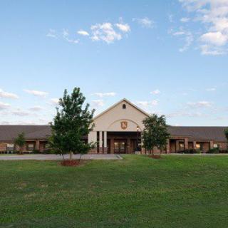 A picturesque view of a school building with a spacious lawn and clear sky.