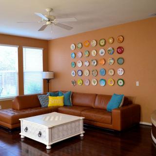 A cozy living room featuring a leather sectional sofa, colorful wall art, and a white coffee table.