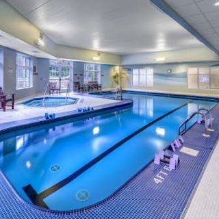 A serene indoor swimming pool area featuring a hot tub and comfortable seating.