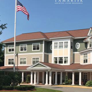 A three-story building with an American flag in front, featuring classic architectural design.