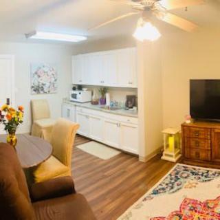 A cozy living space featuring a kitchenette, seating area, and television with wooden flooring.