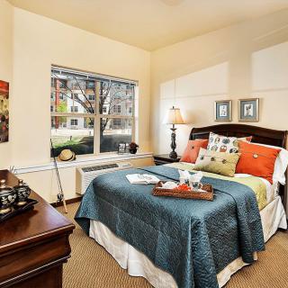 A cozy and well-decorated bedroom with a large bed, lamp, and window view.