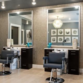 A modern beauty salon interior with stylish chairs and large mirrors.