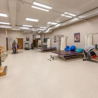A spacious physical therapy gym equipped with various exercise machines and rehabilitation tools.