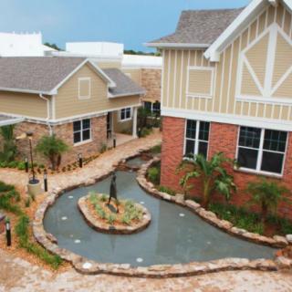 A scenic view of buildings surrounding a small landscaped pond and garden walkway.