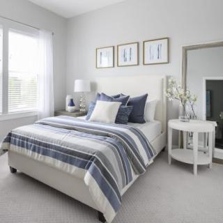 A modern minimalist bedroom with a neatly made bed, decorative pillows, and contemporary furnishings.
