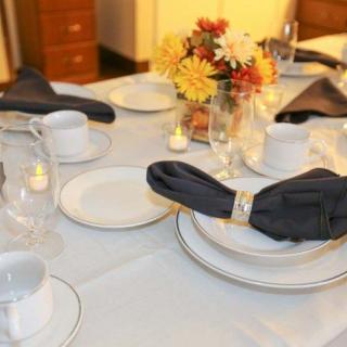 An elegantly set dining table with a floral centerpiece and candles.