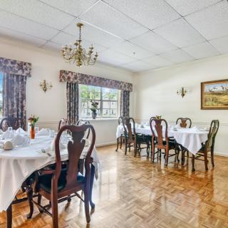 A traditional dining room with elegantly set tables and a chandelier.