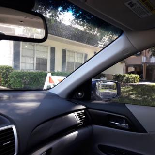 View from inside a car with a house and landscaping in the background.