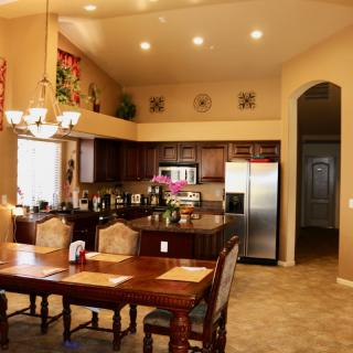 A modern open kitchen with a dining area featuring wooden furniture and stainless steel appliances.