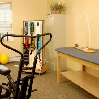 A rehabilitation room equipped with exercise equipment and a treatment table.