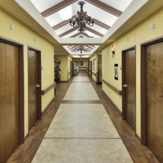 A long, well-lit hallway with a series of doors and a decorative chandelier on the ceiling.