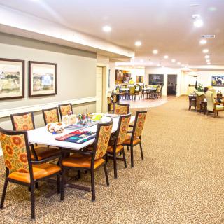 A spacious and well-lit dining area with a long table and chairs, adorned with elegant decor.