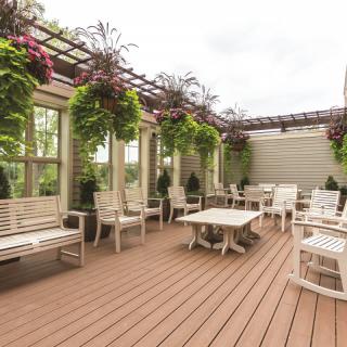 A cozy outdoor patio with wooden furniture and lush hanging plants.