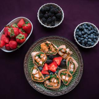 A platter of assorted canaps surrounded by bowls of strawberries, blackberries, and blueberries.