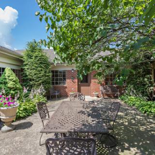 A cozy outdoor dining space surrounded by lush greenery and vibrant flowers.