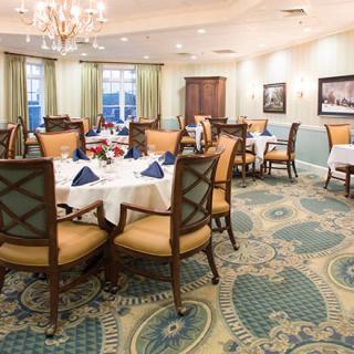 Elegant dining room with neatly arranged tables and chairs, featuring a chandelier and tasteful decor.