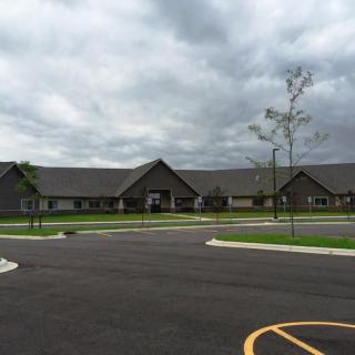 A large building with an empty parking lot under a cloudy sky.