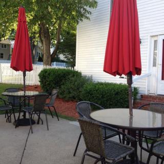 A peaceful outdoor patio with tables, chairs, and red umbrellas.