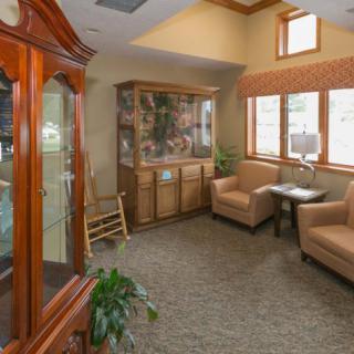 A cozy living room area with armchairs, a cabinet, and a large window allowing natural light.