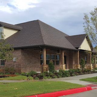 A modern residential building with a brick facade and a well-maintained lawn.