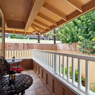 A cozy balcony with seating and a view of lush greenery.