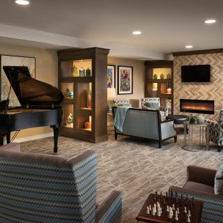 A modern living room with a piano, fireplace, and cozy seating area.
