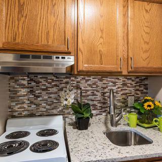 A modern kitchen with wooden cabinets, a stovetop, and a stylish backsplash.