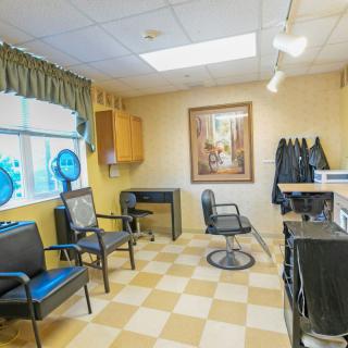 A cozy hair salon interior with chairs, a mirror, and a checkered floor.