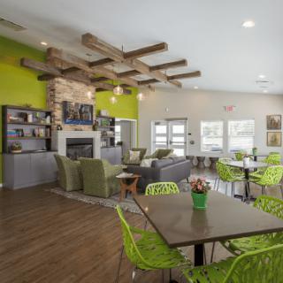Modern interior with vibrant green accents and a cozy seating area featuring a fireplace and wooden beam ceiling.