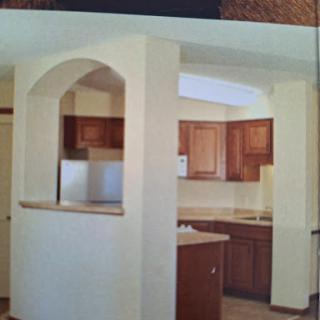A cozy kitchen featuring wooden cabinets and an open archway that connects to the dining area.