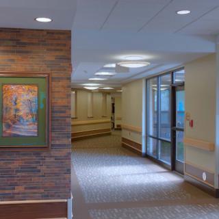 A well-lit corridor in a hospital with decorative art on the wall.