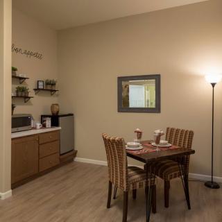 A cozy dining area with a small table set for two, adjacent to a kitchenette.