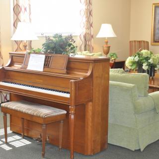 A cozy living room with a wooden piano and comfortable seating.