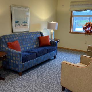 A cozy living room with a blue sofa, red cushions, and a warm atmosphere.