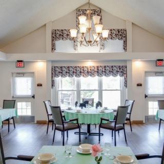 A bright and elegant dining room with neatly arranged tables and a chandelier.