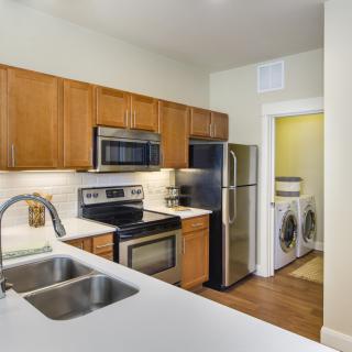 A modern kitchen with stainless steel appliances and an adjacent laundry room.