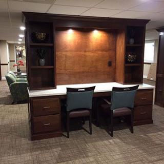 A wooden office desk with integrated shelving and two chairs in a well-lit room.