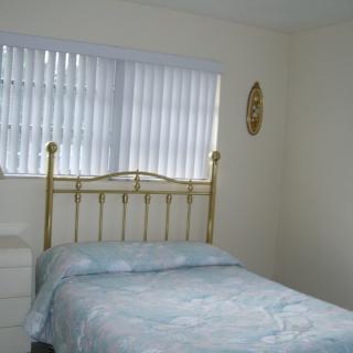 A simple bedroom with a metal bed frame and window blinds.