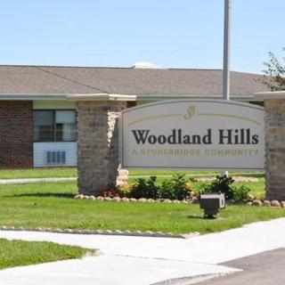 Entrance sign for Woodland Hills against a backdrop of a building and landscaped area.