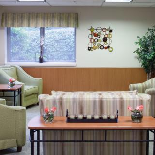 A cozy waiting room with comfortable seating, a central table, and decorative wall art.