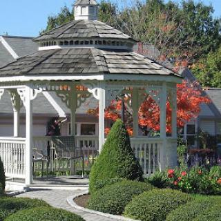 A charming gazebo surrounded by beautifully manicured gardens and vibrant autumn leaves.