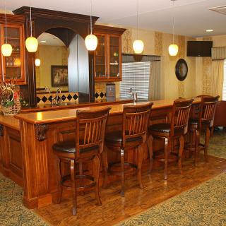 A cozy wooden bar with high chairs and ambient lighting.