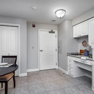 A compact kitchen area with white cabinets and a small dining table, designed in a modern minimalist style.