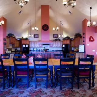 A spacious kitchen and dining area with high ceilings, featuring wooden furniture and chandeliers.