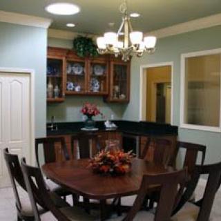 A cozy dining room with a wooden table surrounded by chairs, featuring a chandelier and decorative cabinet.