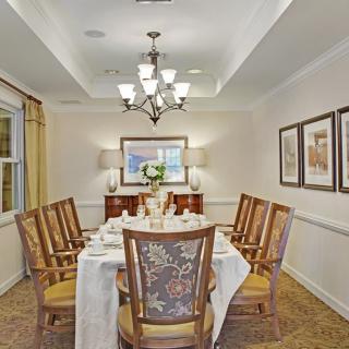 A well-decorated dining room with a central table, surrounded by wooden chairs, and illuminated by an elegant chandelier.