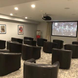 A cozy home theater room with multiple armchairs facing a large projector screen.