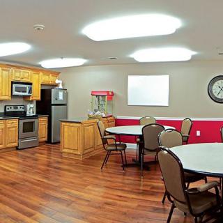 A modern kitchen and dining area with wooden floors, featuring appliances like a stove and fridge, along with tables and chairs for seating.
