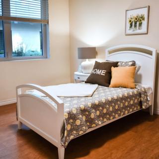 A cozy bedroom with a single bed, decorative pillows, and warm lighting.
